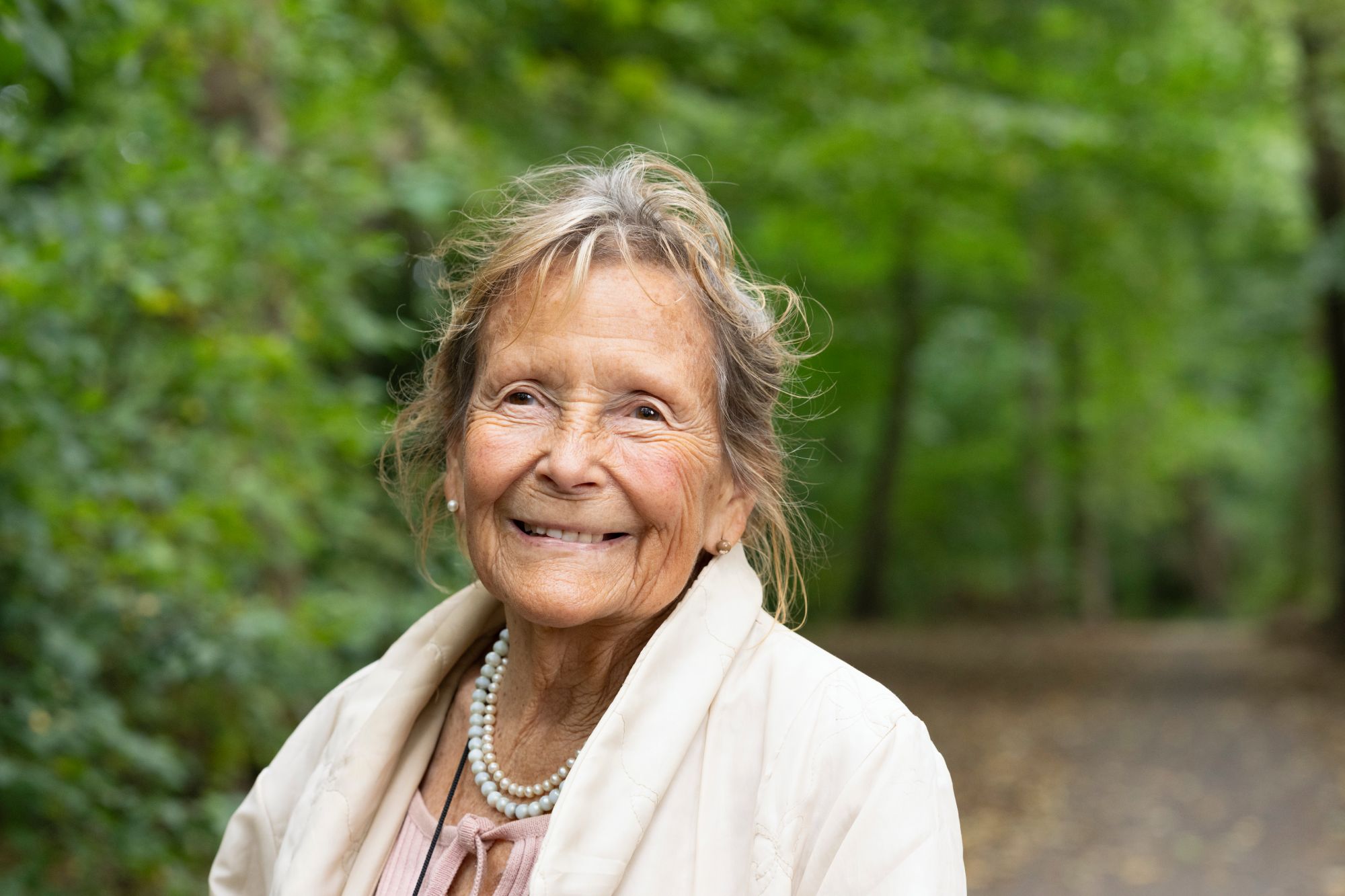 Een portretfoto van een oude vrouw in het bos tijdens de dagbesteding