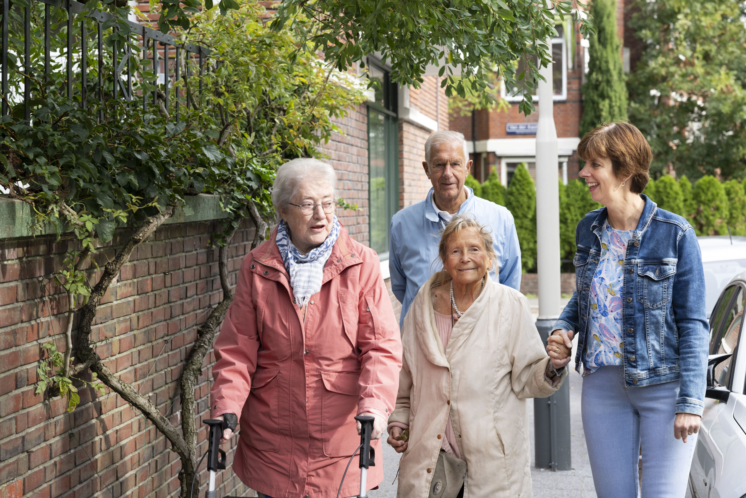 Een afbeelding van drie ouderen die een wandeling maken met hun begeleider tijdens de dagbesteding