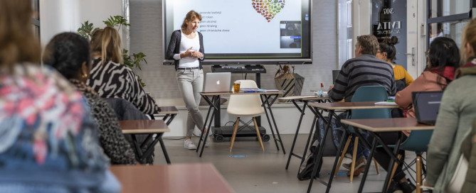 Afbeelding van een vrouw die les geeft in een klas.