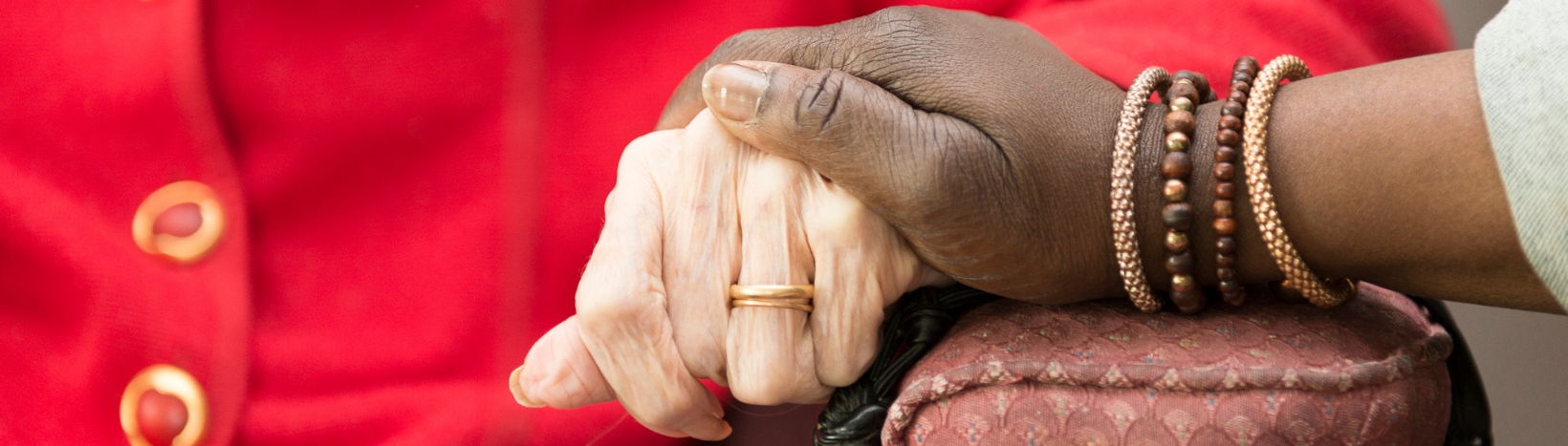 Een afbeelding waarbij de hand van een oudere vrouw word vast gehouden