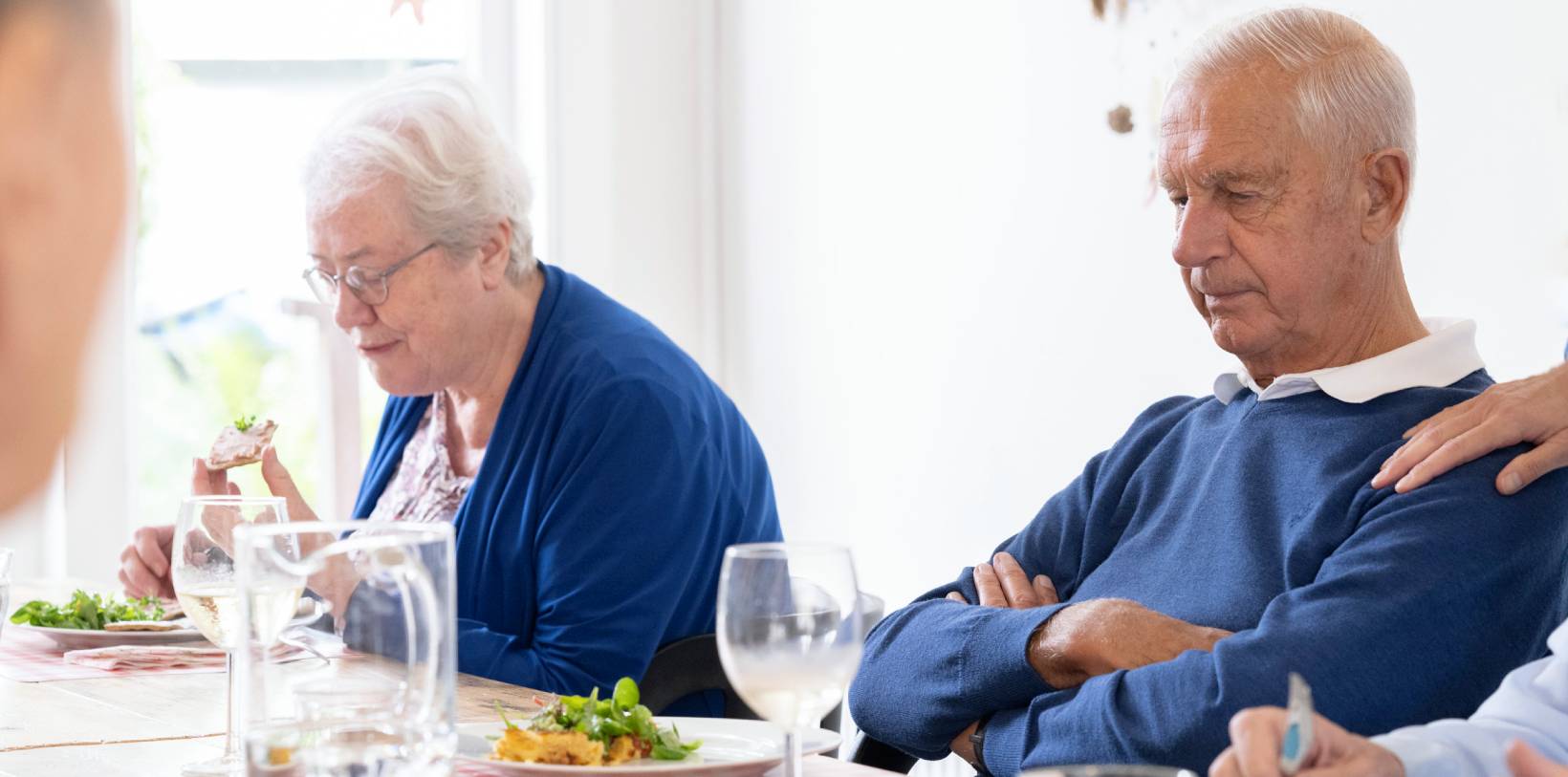 Een afbeelding van een dagbesteding waarbij je twee oudere mensen ziet eten aan een tafel